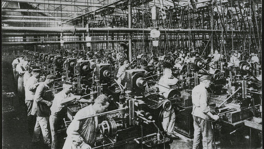 Ouvriers en casquette alignés devant des machines-outils dans un atelier, photographie ancienne, article sur Bernanos