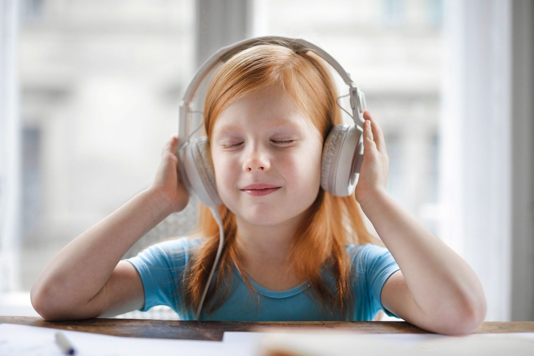 Une petite fille, un casque sur les oreilles, écoute une histoire les yeux fermés